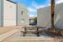 Charming outdoor area with a picnic table and grill set against a modern apartment backdrop, perfect for gatherings and leisure under the blue sky.