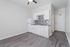 Modern apartment kitchen with sleek white cabinets, stylish backsplash, and dark wood laminate flooring.