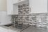 Modern kitchen design with sleek mosaic backsplash, elegant white cabinetry, and efficient cooktop.