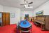 Inviting entertainment room with bright red carpet, poker table, vintage piano, and classic decor, perfect for socializing.
