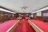 Inviting recreation room featuring multiple billiard tables, elegantly carpeted in red, with vintage wood accents and ample seating.