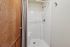 Elegant bathroom with modern enclosed shower featuring sleek fixtures and a stylish wood door accent.