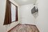 Cozy room with elegant wooden floors, a wall-mounted TV, and a bright window dressed with rich brown curtains.