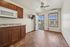 Bright and inviting apartment space featuring polished wood flooring, modern cabinets, and a stylish ceiling fan, leading to a private balcony with scenic views.