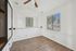 Bright and airy room with elegant wood flooring, large mirrored closet, and abundant natural light through sizable windows.