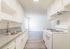 Bright and modern kitchen with sleek white cabinetry, stainless steel sink, and elegant light fixtures, offering a fresh and inviting cooking space.