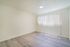 Bright and airy room with modern laminate flooring and large window featuring vertical blinds, perfect for a cozy bedroom or stylish office space.