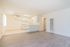 Bright open-concept living space with sleek hardwood floors, modern kitchen with white cabinetry, and a ceiling fan for enhanced comfort.