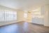 Bright, open-plan living space with hardwood floors and a modern kitchen, featuring large windows for natural light.