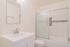 Bright and modern bathroom featuring a clean white vanity, sleek fixtures, and a stylish glass-enclosed bathtub with elegant tile accents.