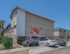 Modern apartment building exterior with parking area, showcasing contemporary architecture and ample natural light.