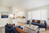 Bright and inviting living room featuring elegant navy sofas, modern decor, and a sleek open-plan kitchen with abundant natural light.