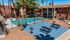 Inviting apartment complex showcasing a sparkling swimming pool, surrounded by cozy seating areas and lush palm trees.