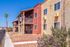 Charming apartment building with colorful stucco facade, balconies, and vibrant landscaping under a clear blue sky.