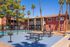 Charming apartment complex with a beautiful pool area and outdoor seating, surrounded by lush palm trees and vibrant landscaping.