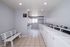 Modern and bright communal laundry room featuring multiple washing machines, tiled floors, and a cozy white bench under soft lighting.