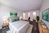 Inviting bedroom with elegant decor, featuring a plush bed, modern nightstands, and vibrant art, surrounded by stylish flooring and soft lighting.
