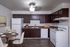 Modern kitchen with sleek dark cabinets, a cozy dining area, and contemporary appliances creating a welcoming atmosphere.