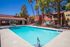 Vibrant apartment complex with a pristine swimming pool surrounded by lush palm trees and welcoming outdoor seating.
