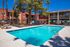Vibrant apartment complex featuring a sparkling swimming pool surrounded by lush palm trees, perfect for relaxation and leisure.
