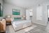 Virtually staged bedroom with modern decor, highlighting a comfortable bed, sleek nightstands, and vibrant artwork, offering a glimpse of a spacious walk-in closet.