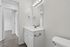 Modern bathroom with sleek white vanity, large mirror, and elegant lighting, featuring a stylish faucet and durable flooring.
