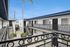 Modern apartment complex with stylish wrought iron railings, showcasing an open corridor and lush tropical touches under a clear blue sky.