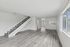Bright, open floor plan apartment featuring elegant wood flooring, a modern staircase, and ample natural light from large windows.