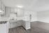 Bright, modern kitchen with sleek cabinetry and open living space featuring elegant hardwood flooring.