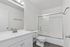 Bright and modern bathroom with sleek vanity, large mirror, and glass-enclosed shower.