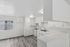 Bright and modern kitchen with white cabinetry, a double sink, and sleek built-in stove, set against elegant light wood flooring.