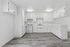Bright modern kitchen with sleek white cabinetry and stainless steel stove, complemented by stylish wood flooring.