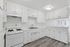 Bright and airy kitchen with sleek white cabinetry, modern gas stove, and elegant wood-style flooring, perfect for culinary enthusiasts.
