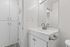 Modern bathroom with sleek white cabinetry, elegant faucet, and large mirror, reflecting contemporary design.