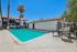 Inviting apartment complex pool area with lounge chairs, palm trees, and a clear blue sky.