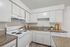 Inviting kitchen with sleek white cabinetry and modern appliances, featuring a cozy countertop space for easy meal preparation.