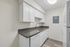 Modern kitchen with sleek white cabinetry, stylish dark countertops, and stainless steel appliances in a bright, compact space.
