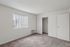 Bright and airy bedroom with large window and cozy carpet, featuring a spacious closet with sliding doors.