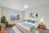 Chic bedroom with modern decor, large window view, and vibrant artwork in a virtually staged setting.
