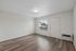 Bright and modern living area with elegant hardwood flooring, large window, and stylish ceiling light, perfect for cozy relaxation.