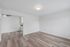 Bright, modern apartment with elegant wood flooring and a sleek ceiling fan, leading to a cozy kitchen area.