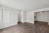 Inviting living space with elegant wood flooring and ample natural light, opening into a cozy kitchen area. Ideal for modern living.
