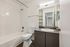 Modern bathroom featuring sleek white tiling, elegant vanity, and a spacious bathtub for ultimate relaxation.