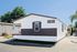 Modern mobile home with sleek wood accents and a welcoming front porch, nestled in a sunny, serene neighborhood.