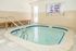 Inviting indoor spa room featuring a cozy whirlpool with modern tile finishes, perfect for relaxation and rejuvenation.
