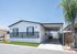 Modern manufactured home with sleek exterior design, covered driveway, and manicured front lawn, offering spacious outdoor living.