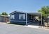Charming mobile home with modern exterior, featuring a sleek blue facade, white trim, and a spacious covered carport, ideal for comfortable residential living.