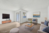 Bright and modern living room with elegant furniture, large TV, and natural light flooding through sliding glass doors.