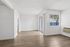 Bright and open living space with modern wood flooring, large windows, and a sliding glass door leading to a private patio.