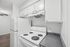 Modern and cozy kitchen with sleek white appliances, ample cabinetry, and a spacious countertop, perfect for cooking enthusiasts.